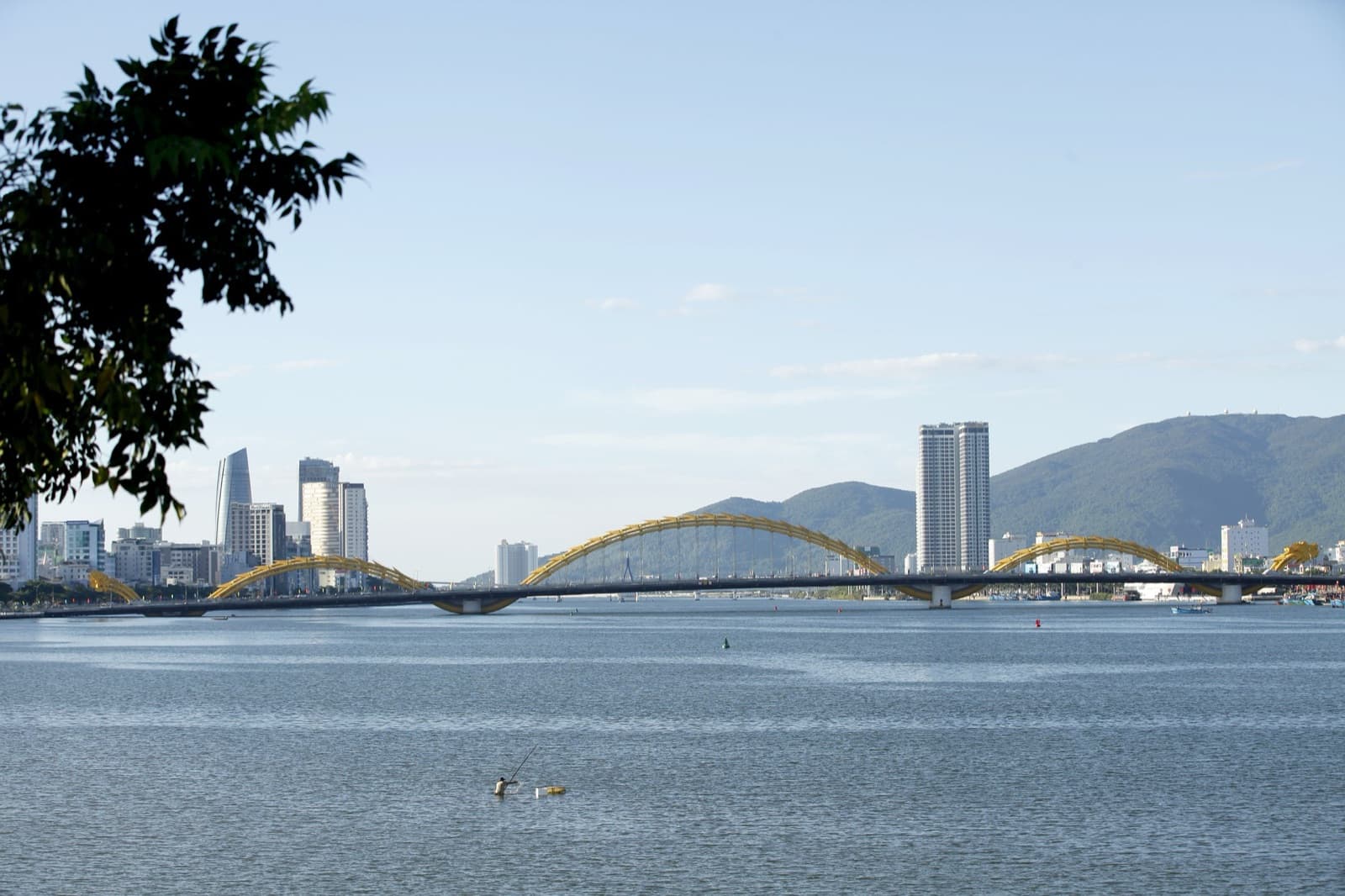 Da Nang's Dragon Bridge arching across the Han River, with the city skyline and green hills behind