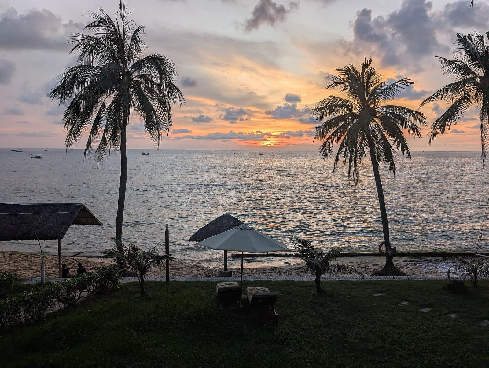 Palm trees silhouetted against a sunset over the sea, seen from a beach on Phu Quoc