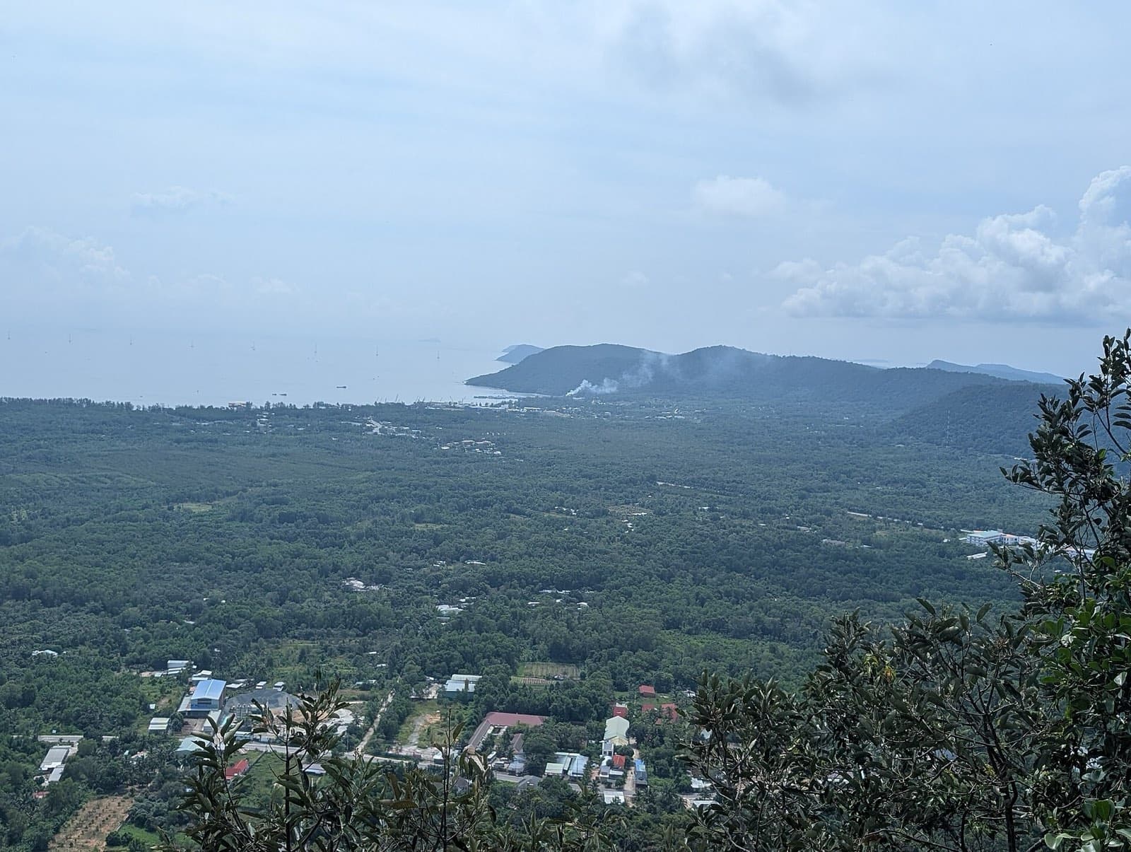 A hilltop view across Phu Quoc's forested interior to the coast, with boats and islands offshore
